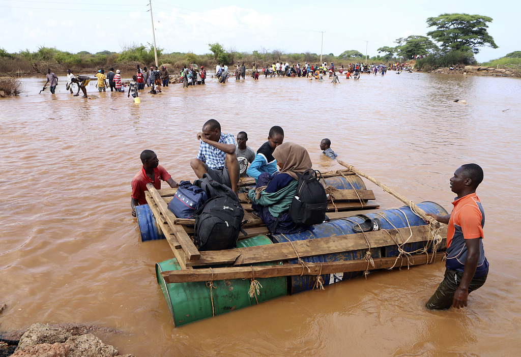 People cross a flooded area on makeshift floating tanks in north eastern Kenya, Thursday, Nov. 30, 2023. Kenya's government is urging people living in flood-prone areas to relocate to higher ground as heavy rains and flash floods continued to wreak havoc across East Africa.